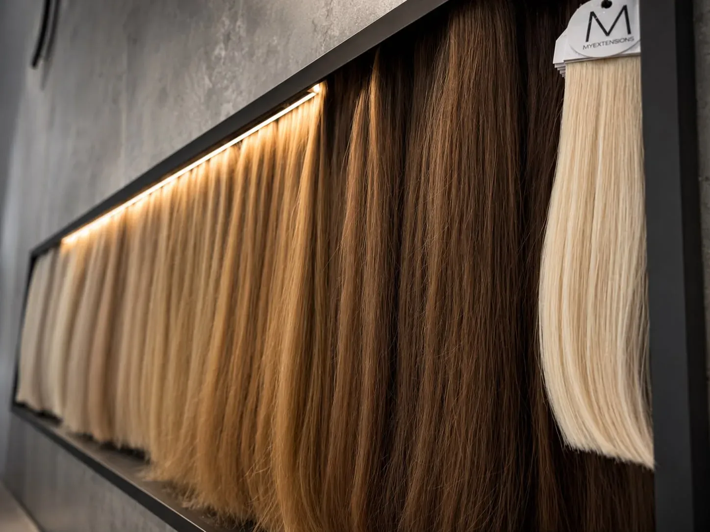 Beleuchtete Echthaarwand mit Extensions-Strähnen im Salon